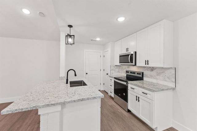 kitchen with hanging light fixtures, appliances with stainless steel finishes, sink, and white cabinetry