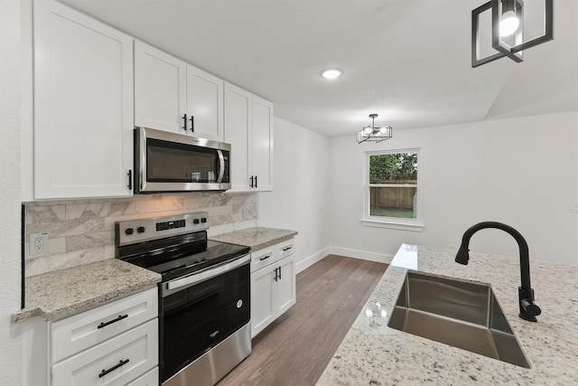 kitchen featuring sink, hanging light fixtures, appliances with stainless steel finishes, and white cabinets