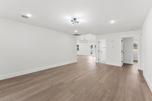 unfurnished living room with a chandelier and wood-type flooring