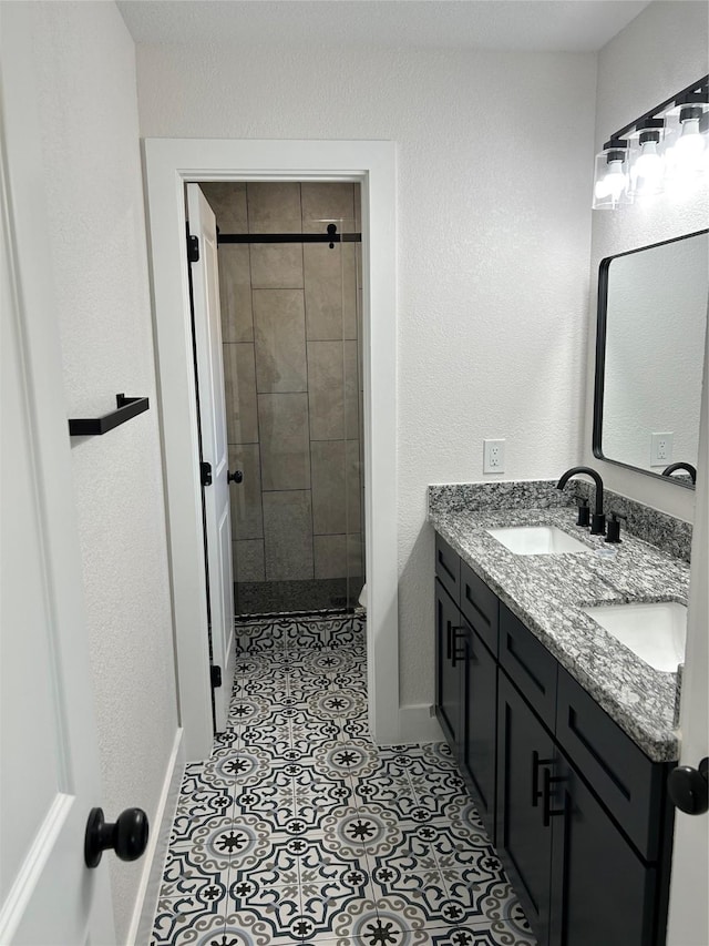 bathroom featuring tile patterned flooring, a tile shower, and vanity