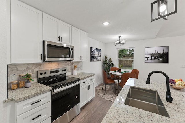 kitchen featuring tasteful backsplash, appliances with stainless steel finishes, an inviting chandelier, dark wood-style floors, and a sink