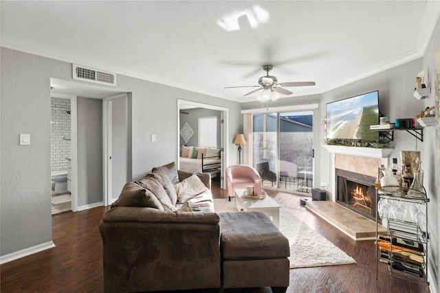 living room featuring ceiling fan, crown molding, a fireplace, and dark hardwood / wood-style floors