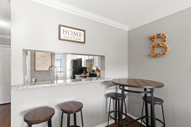 kitchen featuring a kitchen bar, kitchen peninsula, stainless steel appliances, ornamental molding, and light stone counters