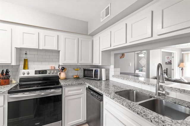 kitchen with appliances with stainless steel finishes, white cabinets, tasteful backsplash, and sink