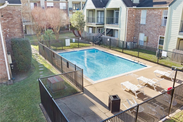 view of swimming pool featuring a lawn, central air condition unit, and a patio