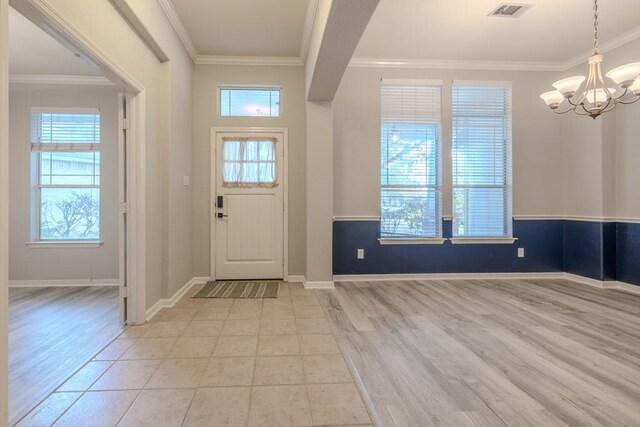 tiled entrance foyer featuring a chandelier and ornamental molding