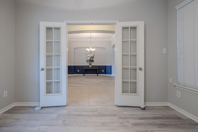 interior space with light wood-type flooring, a chandelier, and french doors