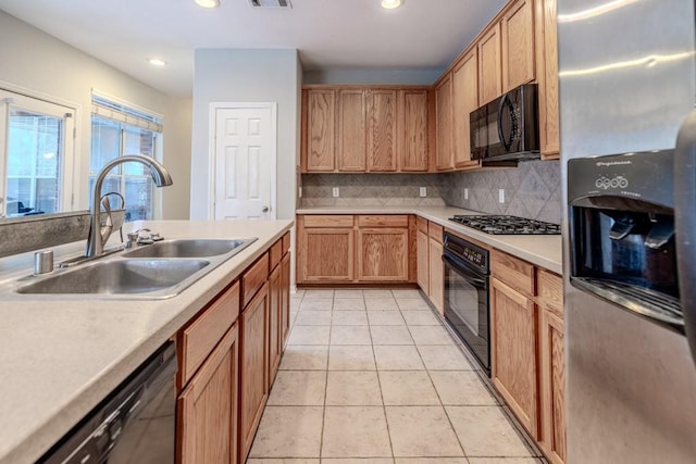 kitchen featuring tasteful backsplash, light tile patterned flooring, sink, and black appliances