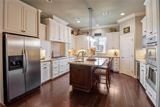 kitchen with a center island with sink, appliances with stainless steel finishes, light stone countertops, a breakfast bar, and sink