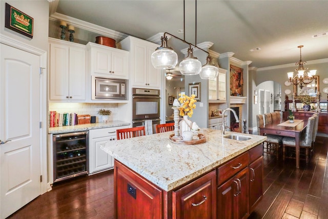 kitchen featuring wine cooler, a center island with sink, sink, appliances with stainless steel finishes, and white cabinets