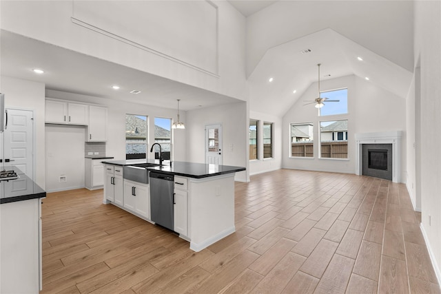 kitchen featuring a high ceiling, white cabinets, stainless steel appliances, sink, and a center island with sink