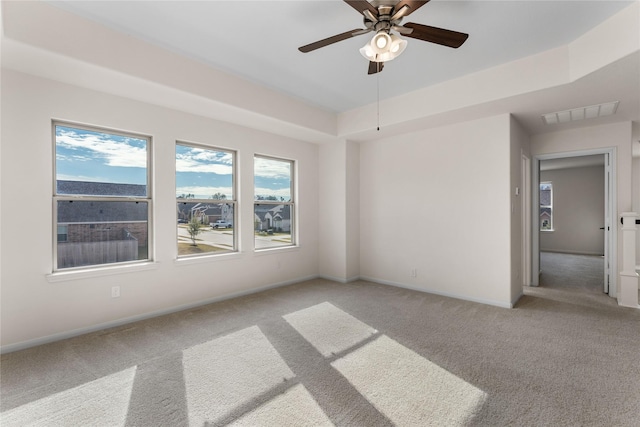 carpeted empty room featuring a raised ceiling and ceiling fan