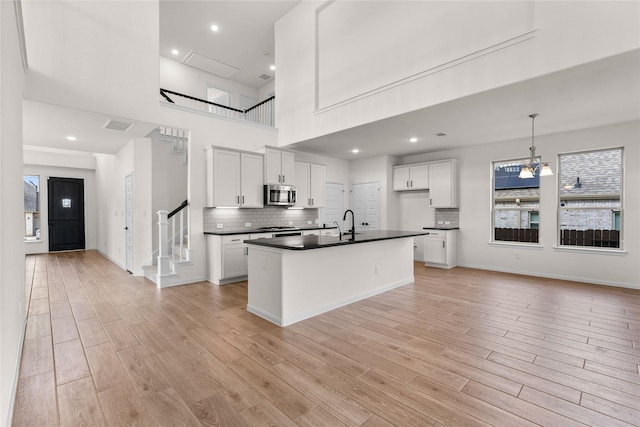 kitchen with white cabinetry, light hardwood / wood-style floors, decorative backsplash, pendant lighting, and sink