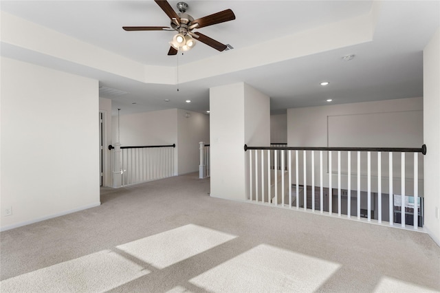 carpeted spare room with ceiling fan and a raised ceiling