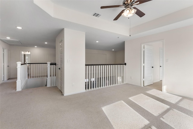 carpeted spare room with a raised ceiling and ceiling fan