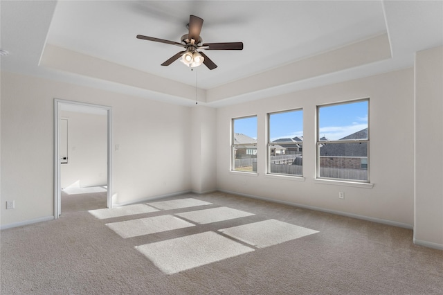 carpeted empty room with ceiling fan and a tray ceiling