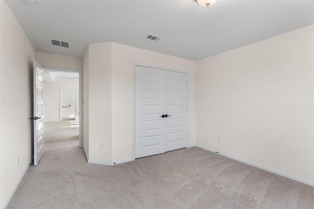 unfurnished bedroom with light carpet and a closet