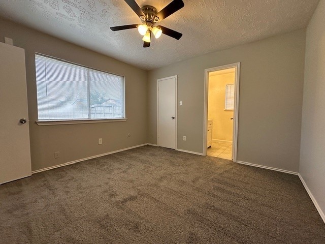 unfurnished bedroom featuring ceiling fan, ensuite bath, carpet, and a textured ceiling