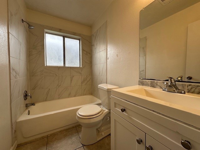 full bathroom featuring toilet, tile patterned flooring, tiled shower / bath, and vanity