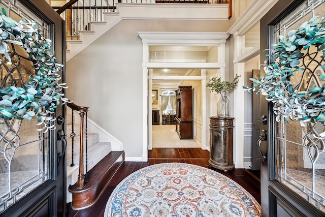 foyer with dark wood-type flooring and crown molding