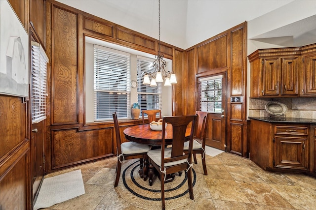 dining space with vaulted ceiling, wooden walls, and an inviting chandelier