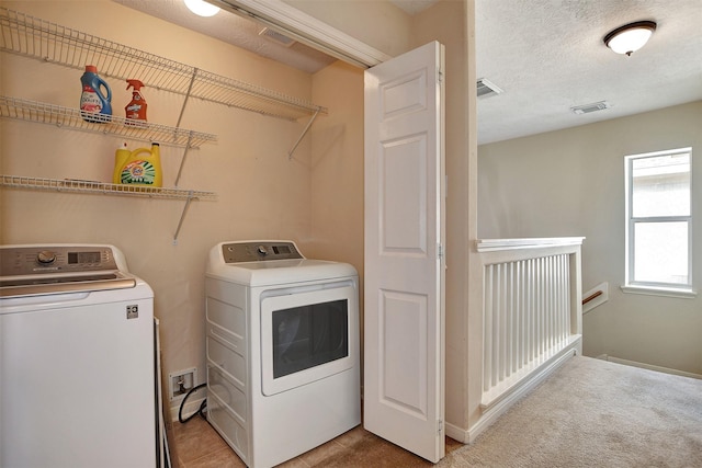 laundry room featuring washer and clothes dryer, light carpet, and a textured ceiling