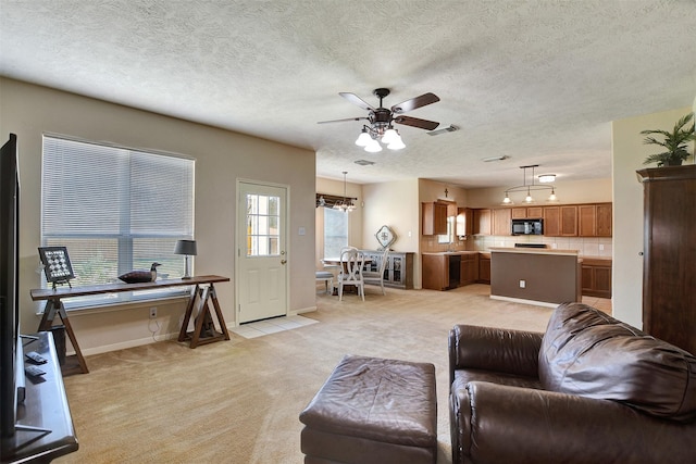 living room with light colored carpet, ceiling fan with notable chandelier, and a textured ceiling