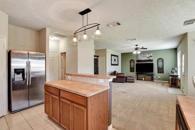 kitchen with stainless steel fridge, ceiling fan, hanging light fixtures, a kitchen island, and light colored carpet