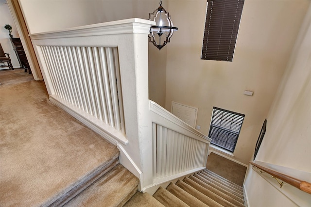 stairway with carpet and a notable chandelier