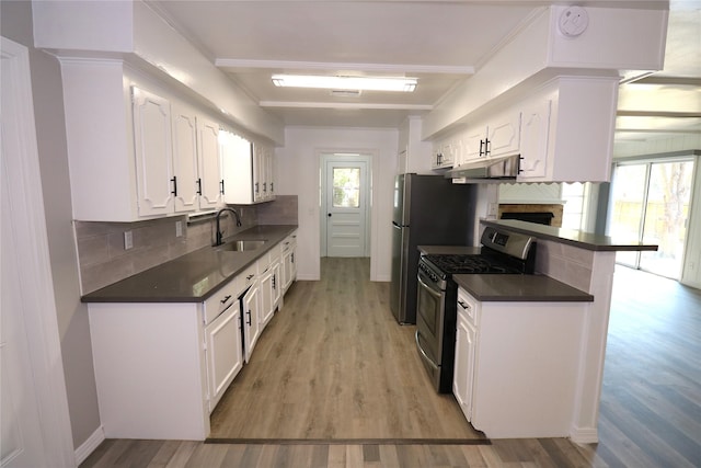 kitchen featuring tasteful backsplash, light wood-type flooring, gas range, white cabinets, and sink