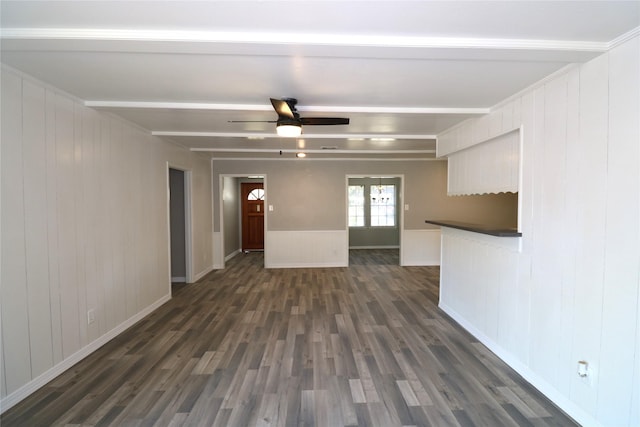 unfurnished living room with dark wood-type flooring, beamed ceiling, and ceiling fan