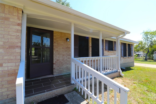 view of exterior entry featuring covered porch and a yard