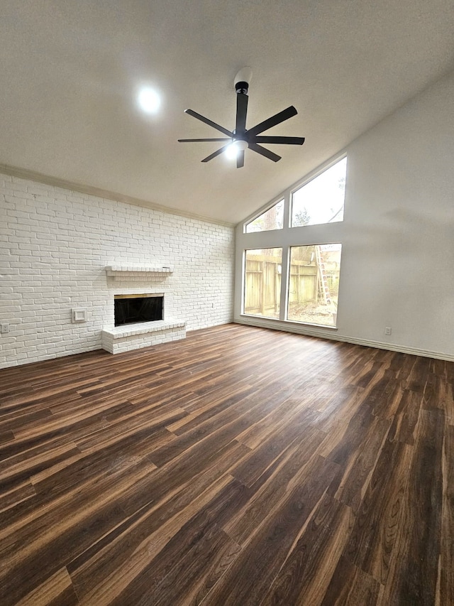 unfurnished living room with ceiling fan, dark hardwood / wood-style floors, brick wall, lofted ceiling, and a fireplace