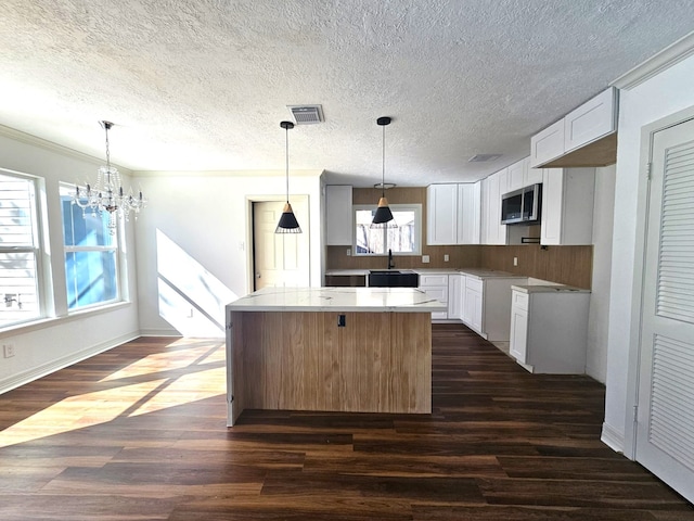 kitchen featuring dark wood-type flooring, a chandelier, white cabinets, and a center island