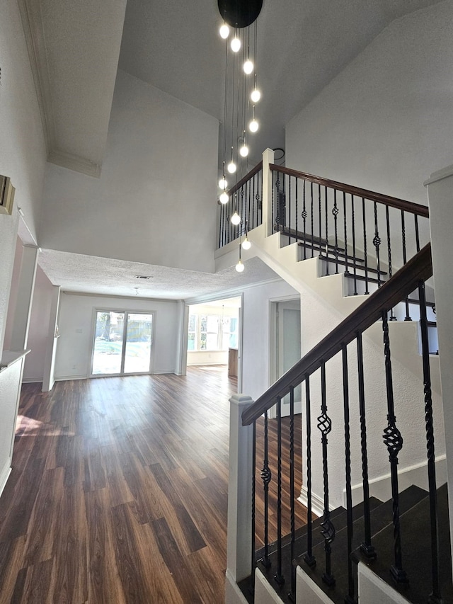 stairs with hardwood / wood-style flooring and high vaulted ceiling