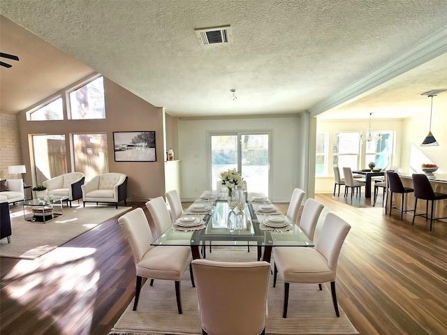 dining area with crown molding, an inviting chandelier, a textured ceiling, and hardwood / wood-style floors