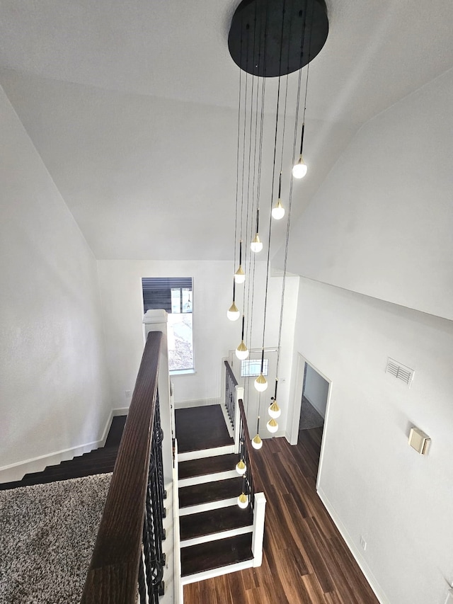 stairway with hardwood / wood-style floors and lofted ceiling