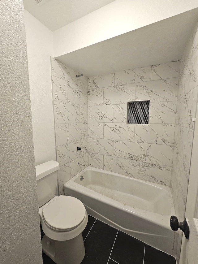 bathroom featuring toilet, tiled shower / bath, and tile patterned flooring