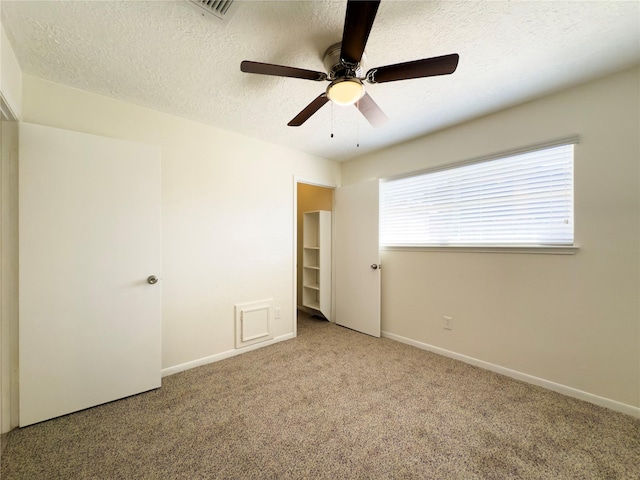 unfurnished room with a textured ceiling, ceiling fan, and carpet floors