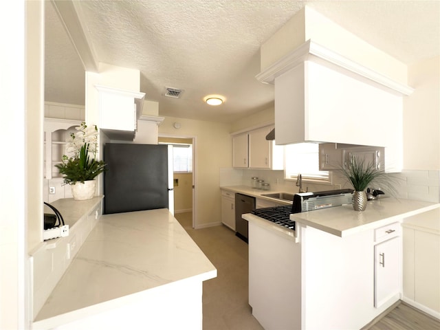 kitchen with kitchen peninsula, sink, black dishwasher, white cabinets, and stainless steel fridge