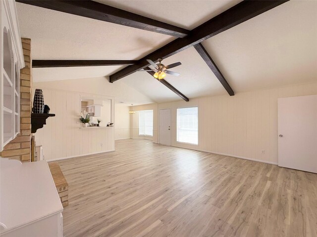 unfurnished living room with light wood-type flooring, ceiling fan, and vaulted ceiling with beams