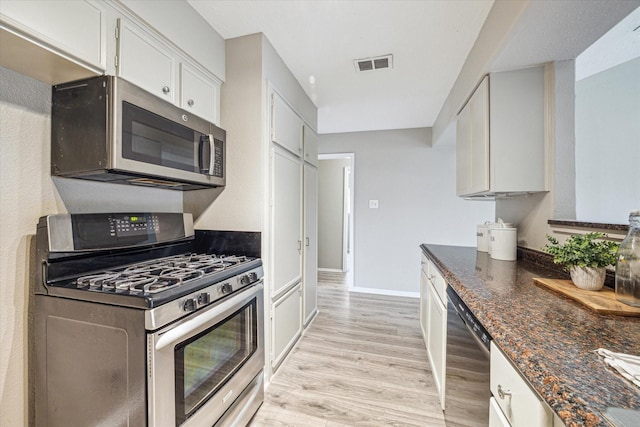 kitchen with light hardwood / wood-style floors, dark stone countertops, stainless steel appliances, and white cabinetry