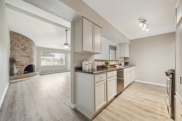 kitchen featuring white cabinets, appliances with stainless steel finishes, a fireplace, sink, and ceiling fan