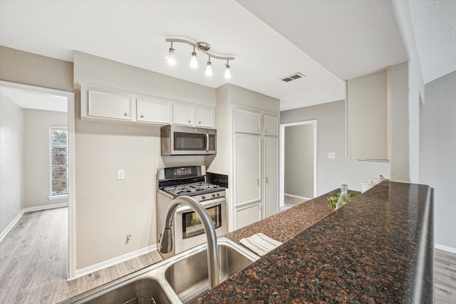 kitchen featuring appliances with stainless steel finishes, light hardwood / wood-style floors, white cabinetry, and sink