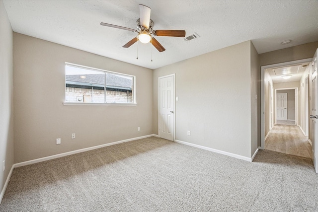 spare room featuring ceiling fan, light colored carpet, and a textured ceiling