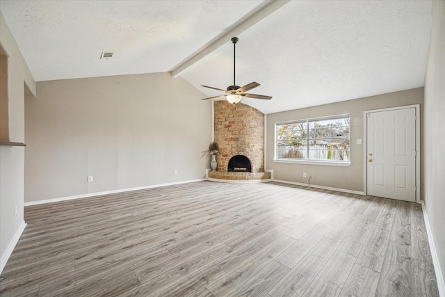 unfurnished living room featuring lofted ceiling with beams, wood-type flooring, a fireplace, and a textured ceiling