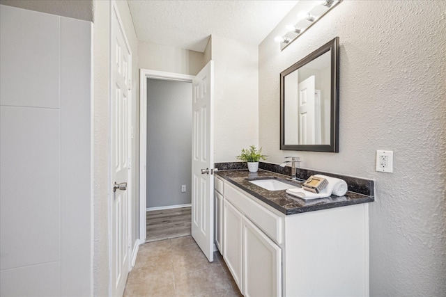 bathroom with a textured ceiling, tile patterned floors, and vanity