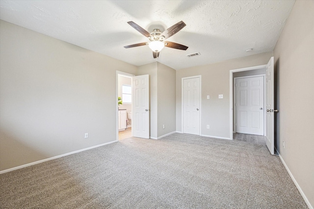 unfurnished bedroom with ceiling fan, a textured ceiling, and light carpet