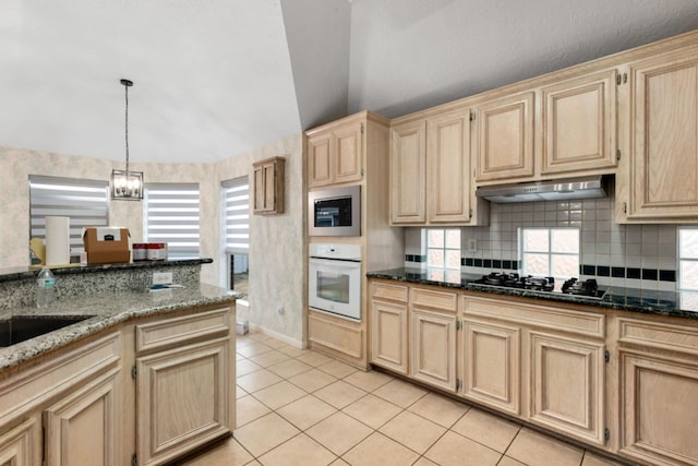 kitchen featuring black gas stovetop, dark stone countertops, oven, and built in microwave