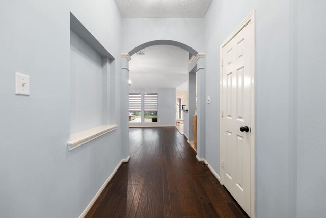 hall featuring dark wood-type flooring and ornate columns